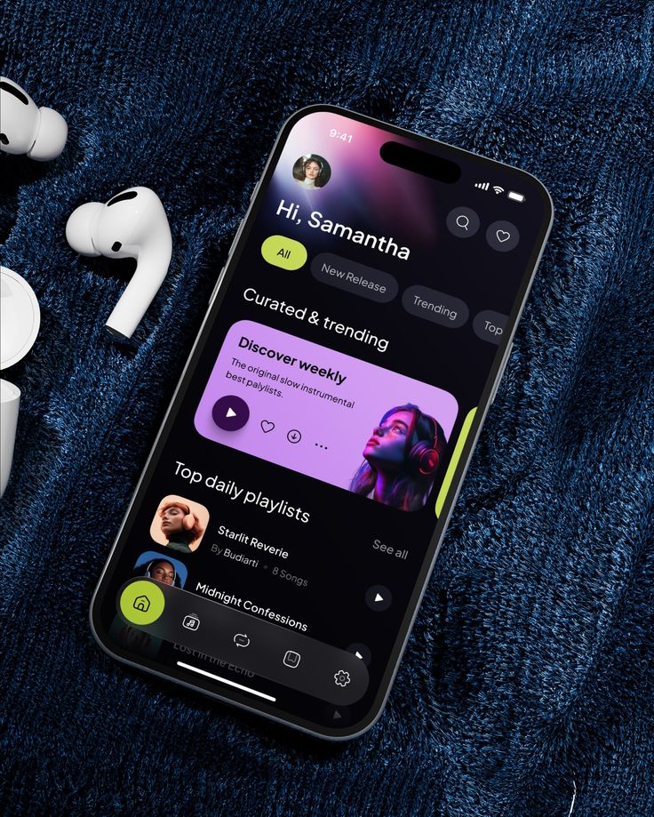 Smartphone displaying a music streaming app interface with playlists, surrounded by earbuds on a textured surface.