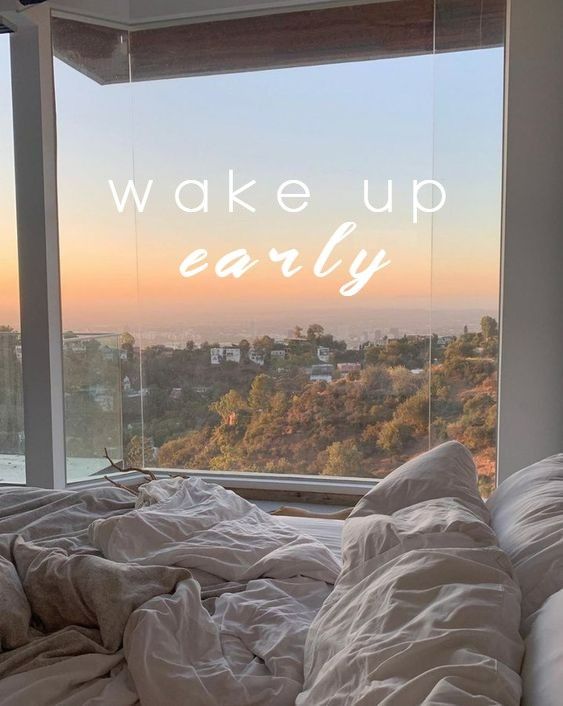 Cozy unmade bed with morning view of hills and sunrise, text wake up early on the window, inspiring peaceful start.