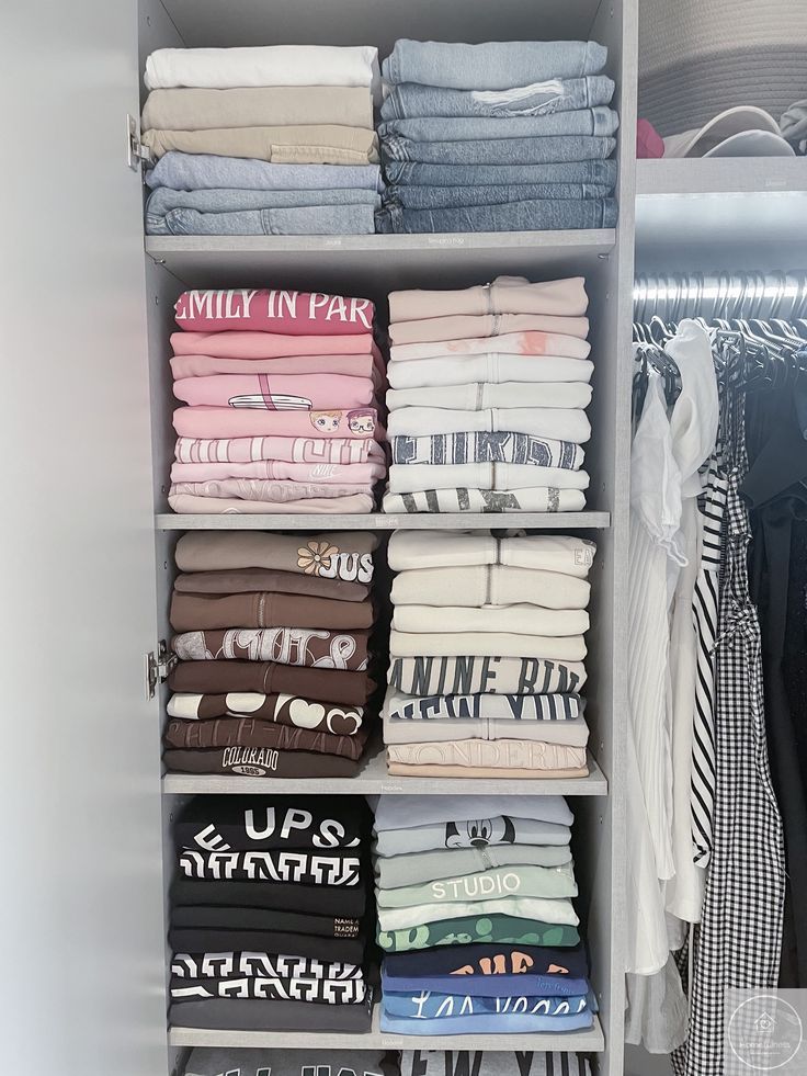 Neatly folded clothes on shelves in a wardrobe, showcasing a range of colors and patterns for organized storage.