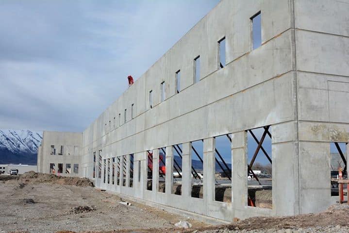 Concrete building under construction with mountain backdrop, showcasing architecture and development progress.