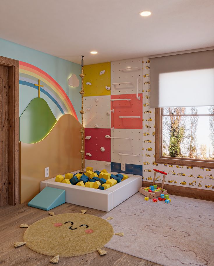 Colorful children's playroom with climbing wall, foam pit, rainbow mural, and sun rug, designed for active play. Functional and Fun Kids’
