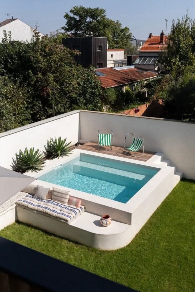 Stylish modern backyard pool area with green lawn, striped deck chairs, and cozy seating for outdoor relaxation.