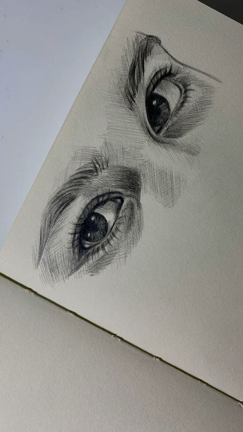 Pencil sketch of expressive eyes on a notebook page, showcasing detailed shading and artistic skill.