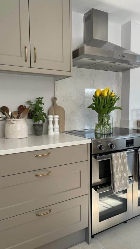 Modern kitchen with stainless steel stove, beige cabinets, yellow tulips, and marble backsplash for a fresh look.