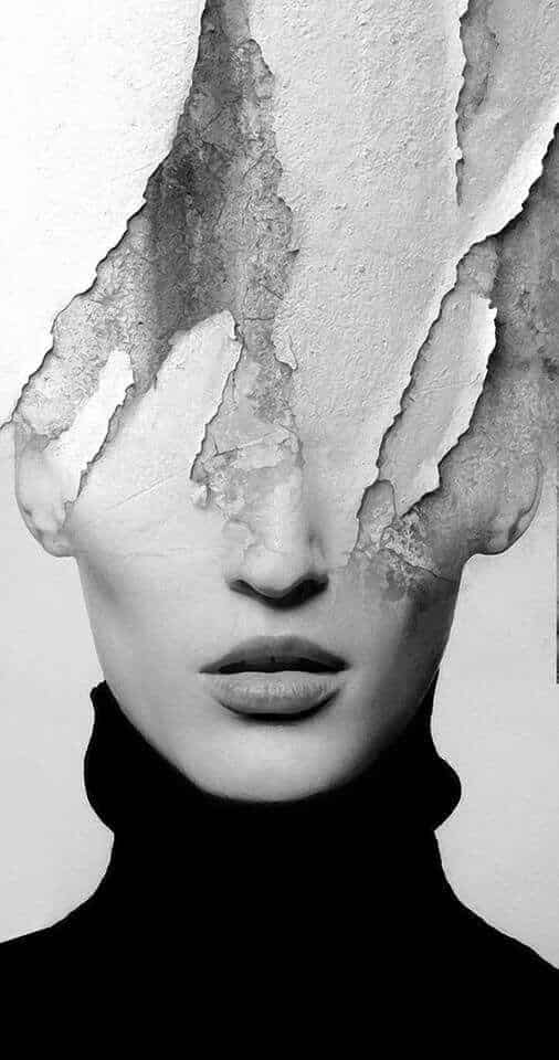 Surreal portrait of a woman with a cracked, peeling facade covering her face, in black and white.