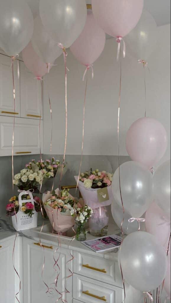 Elegant kitchen scene with pink and white balloons, floral arrangements, and a light, airy atmosphere.