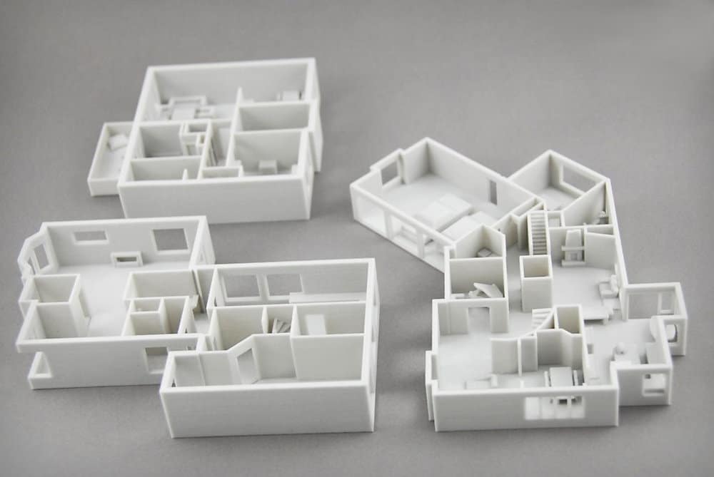 3D-printed architectural models of building floor plans on a gray background.