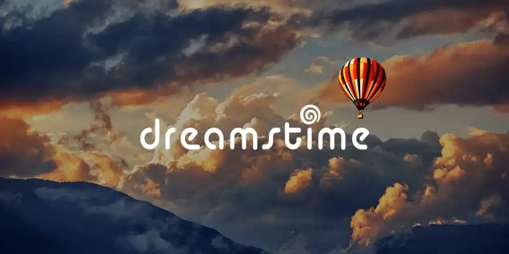 Hot air balloon floating at sunset with Dreamstime logo, colorful sky and clouds, creating a serene and inspiring atmosphere.