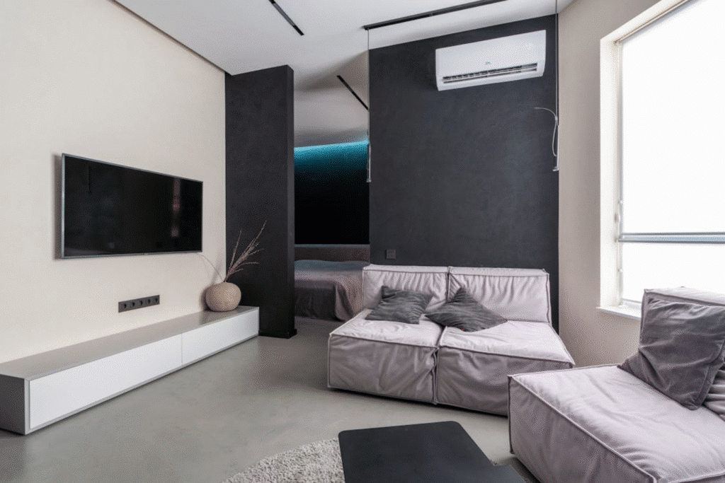 Modern living room with minimalist decor, wall-mounted TV, and cozy gray sofa.