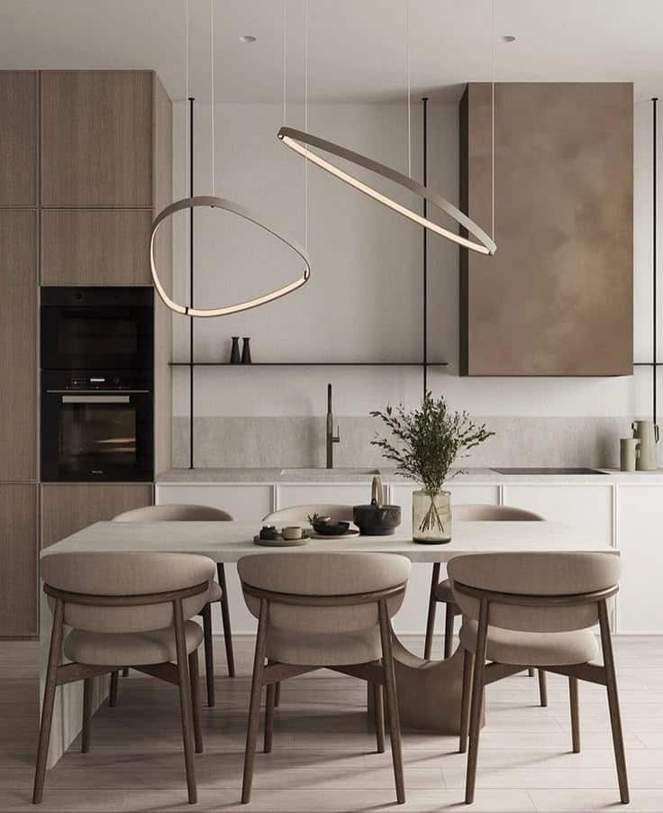 Modern kitchen interior with minimalist design, pendant lights, wooden cabinets, and a dining table with cushioned chairs.