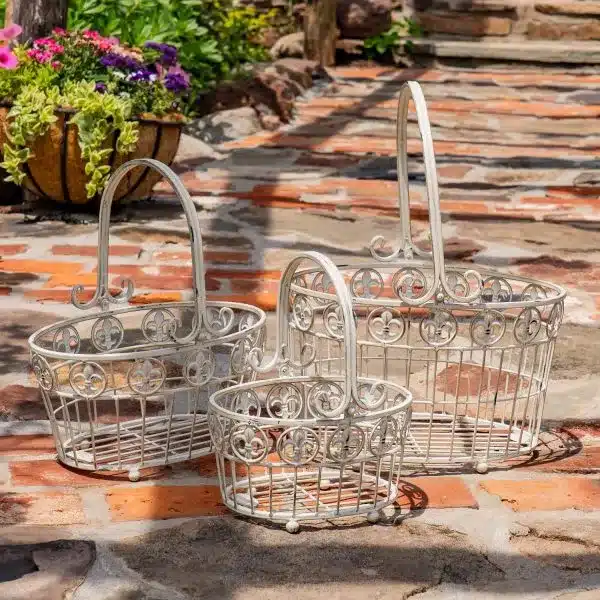 Decorative wire baskets set on rustic patio with plants in background.