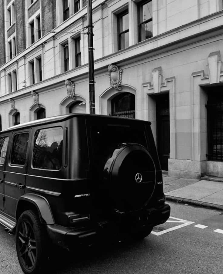 Black Mercedes-Benz G-Class SUV parked on a city street, luxury urban vehicle in black and white.