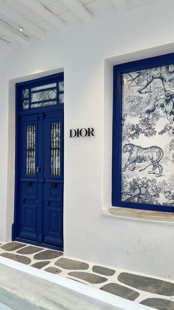 Elegant Dior storefront with blue door and artistic window display.