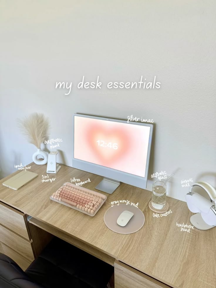 Minimalist desk setup with iMac, pink keyboard, mouse pad, iPad, aesthetic decor, and headphone stand.