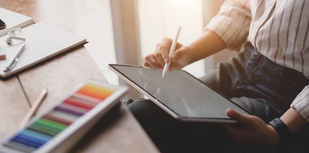 person-using-white-tablet-3759058 Person sketching on tablet with stylus, colorful pencils nearby on a wooden desk. | Sky Rye Design Person sketching on tablet with stylus, colorful pencils nearby on a wooden desk.