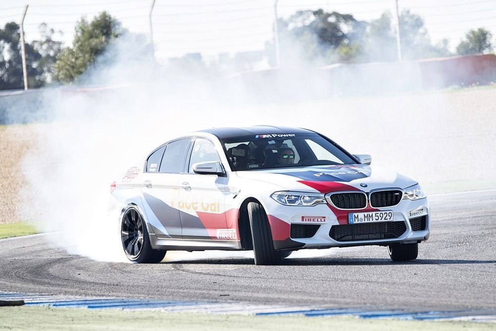 BMW car drifting on the racetrack, creating smoke, showcasing speed and performance.