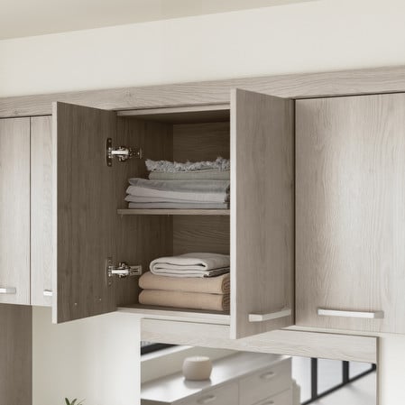 Open wood cabinet with neatly stacked linens and towels on shelves in a modern kitchen setting.