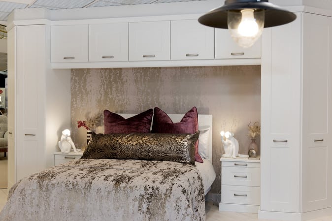 Modern bedroom design with white built-in furniture, plush cushions, and ambient lighting.