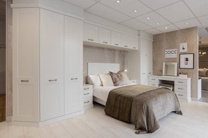 Modern bedroom with white built-in wardrobes, cozy bed, and elegant decor. Perfect for stylish home interiors.