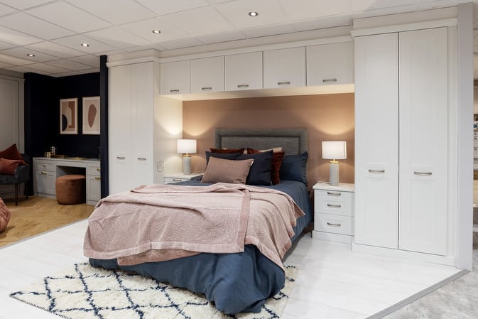 Modern bedroom design with built-in white cabinets, cozy bedding, and warm lighting, featuring a stylish decor accent.