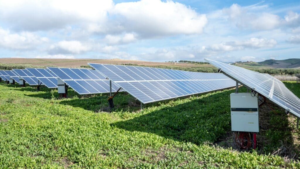 sungrow-emea-VC-m6ULjJ6Y-unsplash Rows of solar panels on a grassy field under a partly cloudy sky, generating renewable energy. | Sky Rye Design Rows of solar panels on a grassy field under a partly cloudy sky, generating renewable energy.