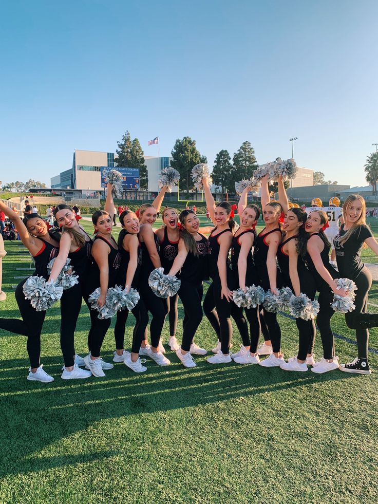 Cheerleading team poses on a sunny field with pom-poms, showcasing team spirit and enthusiasm.