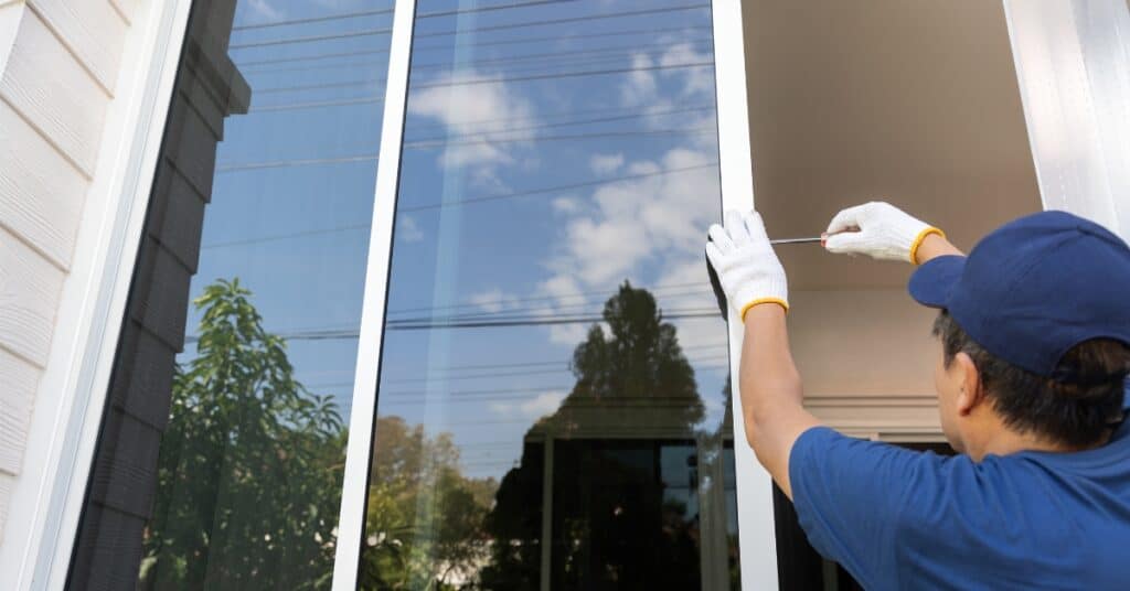 unnamed 84 Worker in blue hat fixing a large window with screwdriver, outdoors on a sunny day. | Sky Rye Design Worker in blue hat fixing a large window with screwdriver, outdoors on a sunny day.