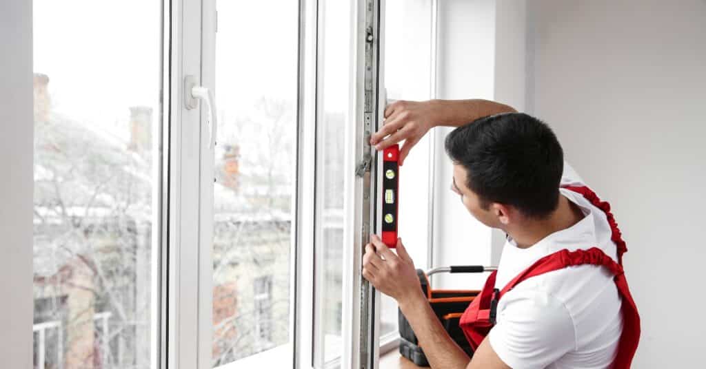 Man using a level to install a window indoors in a modern home renovation setting.