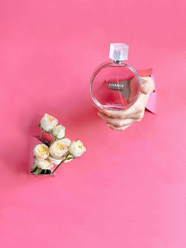 Chanel perfume and white roses on pink background, elegant and feminine arrangement for beauty and luxury theme.