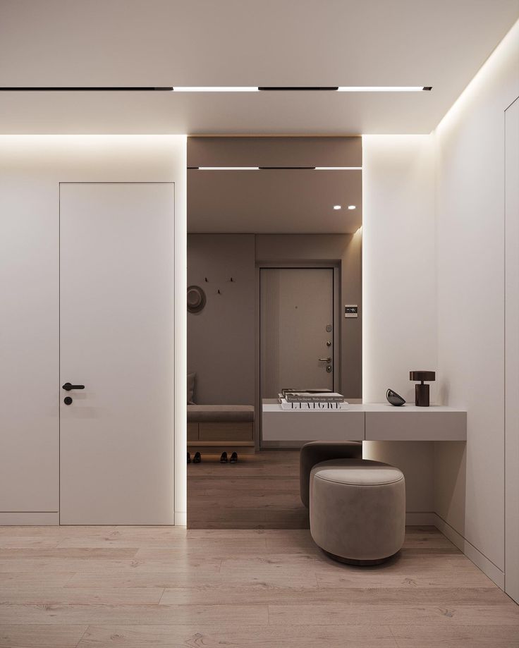 Modern minimalist hallway with sleek lighting, round stool, and pale wood flooring for a contemporary look.