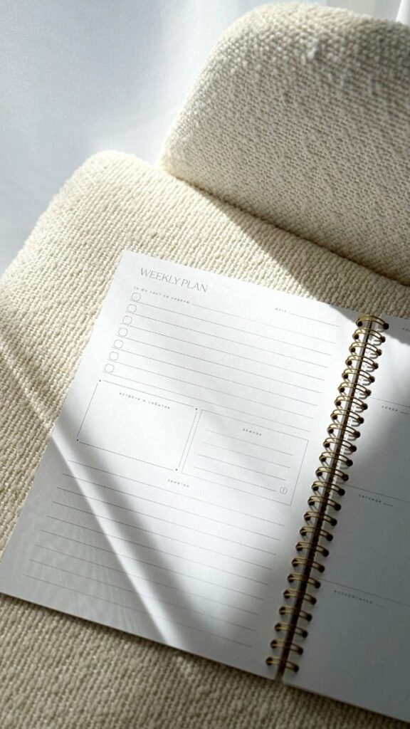 Open weekly planner on a cozy beige chair, illuminated by soft natural light.