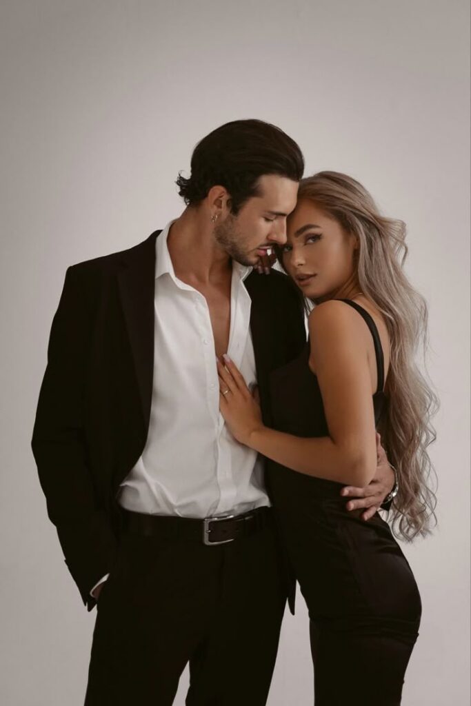 Elegant couple posing in formal attire, showcasing style and romance against a neutral background.