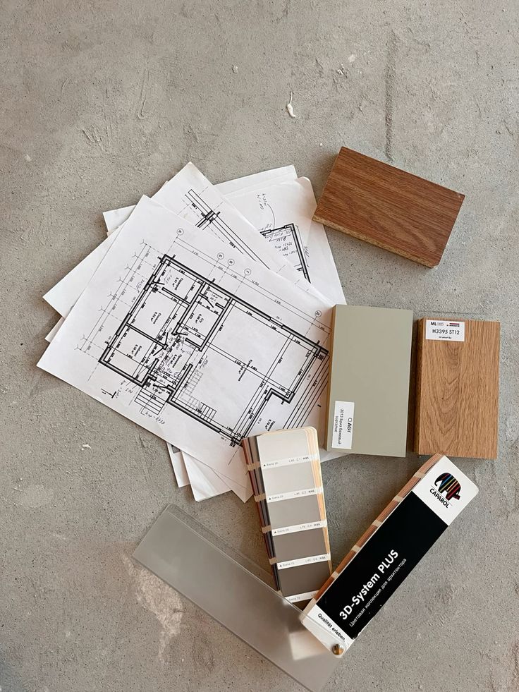 Architectural blueprints with color swatches and wood samples on a concrete background.