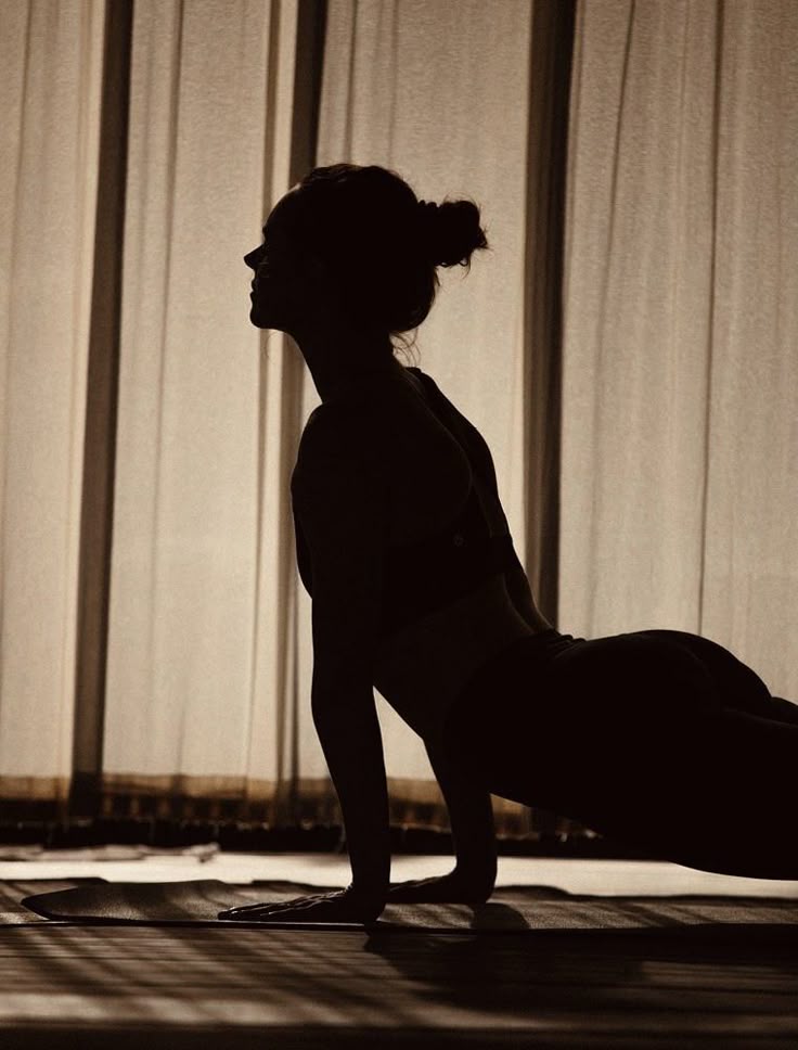 Silhouette of a woman practicing yoga in a serene, sunlit room.