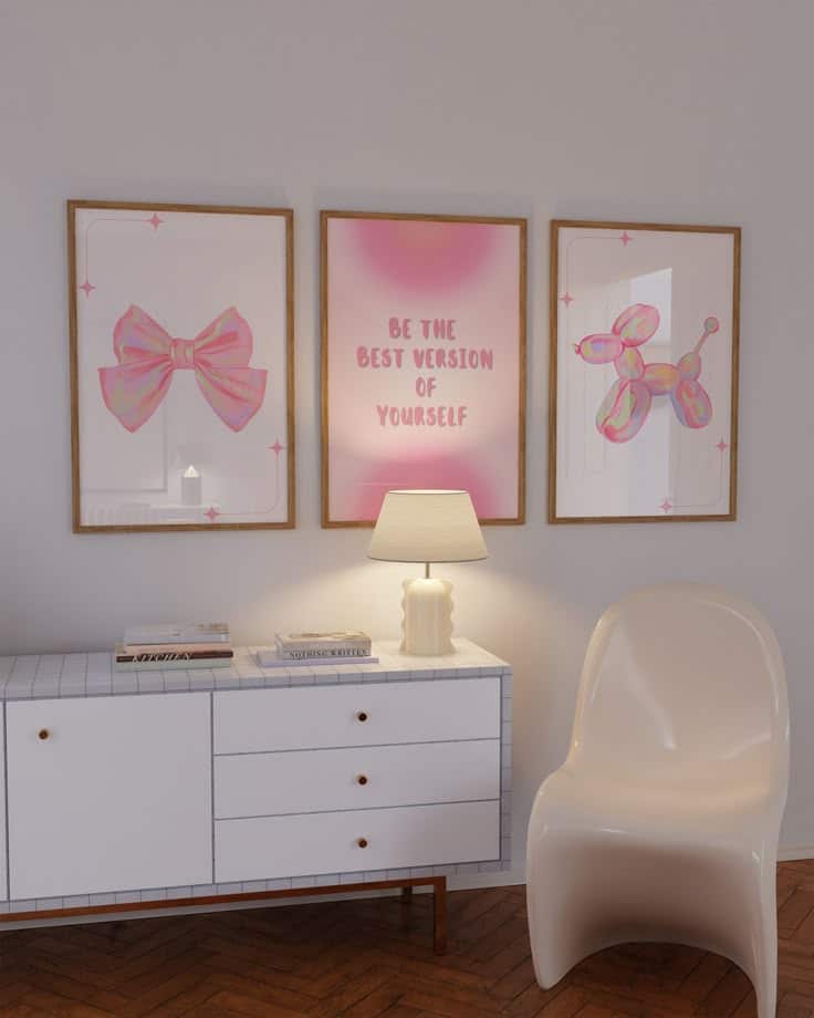 Modern room with motivational artwork, pink decor, white dresser, lamp, and sleek chair. Wall frames inspire positivity.