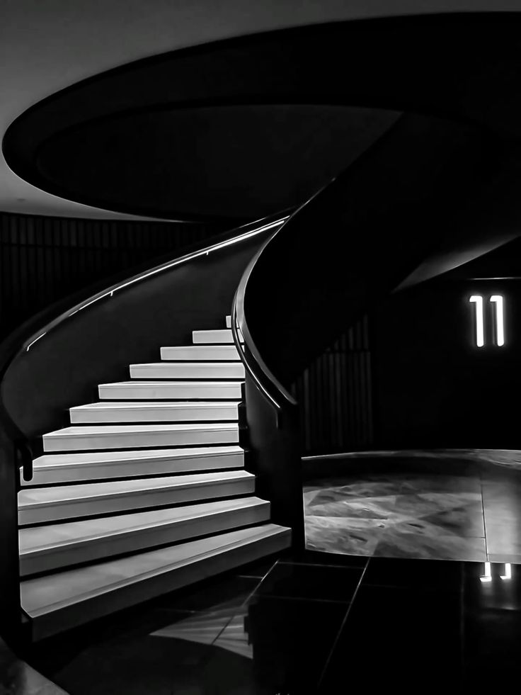 Black and white spiral staircase with illuminated steps and modern design.