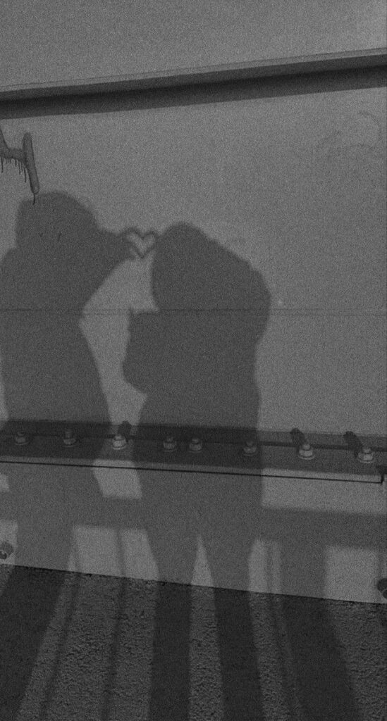 Shadow couple forming a heart with hands on a wall, symbolizing love and connection.