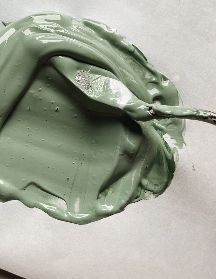 Smooth green paint spread with a palette knife on a white surface.