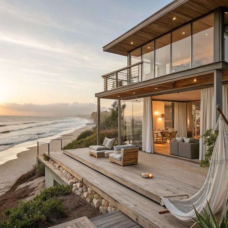 🏝️ Luxury Beach House with Oceanfront Views _ Coastal Dream Home 🌊✨ Modern beachfront house with large windows, wooden deck, hammock, and ocean view at sunset. | Sky Rye Design Modern beachfront house with large windows, wooden deck, hammock, and ocean view at sunset.