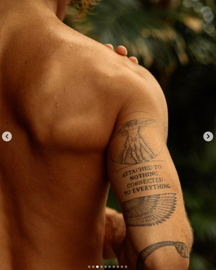 Close-up of a person's tattooed arm featuring a Vitruvian Man design, with text and intricate symbols.
