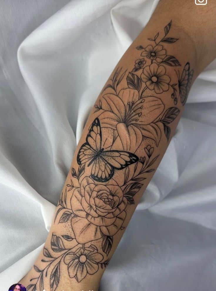 02a12515-4257-4d95-945e-0adf19b5b8cf Arm tattoo with detailed flowers and butterfly design on a fabric background. | Sky Rye Design Arm tattoo with detailed flowers and butterfly design on a fabric background.