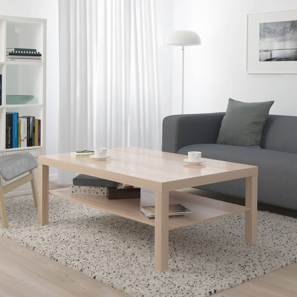 Modern living room with a wooden coffee table, gray sofa, books, and cozy decor.