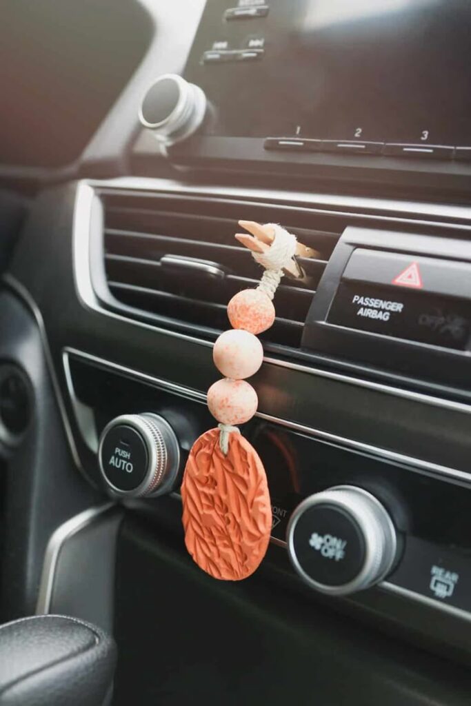 Car dashboard with a handcrafted terra cotta air freshener hanging from the vent, enhancing the vehicle interior.