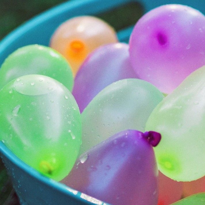 Colorful water balloons in a blue bucket, ready for a fun outdoor activity or summer water fight.