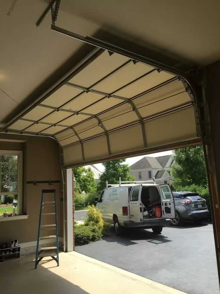 Open garage door with parked van outside, ladder inside, view of residential neighborhood.