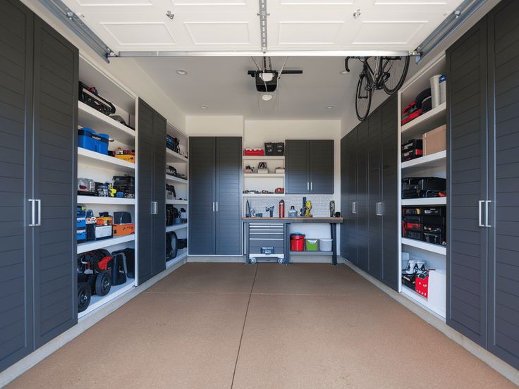 Organized garage with storage cabinets, workbench, and hanging bike. Clean, efficient space for tools and equipment.