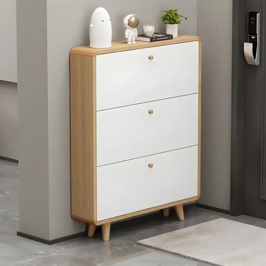 Modern minimalist shoe cabinet with white drawers, wooden frame, and decorative items on top.