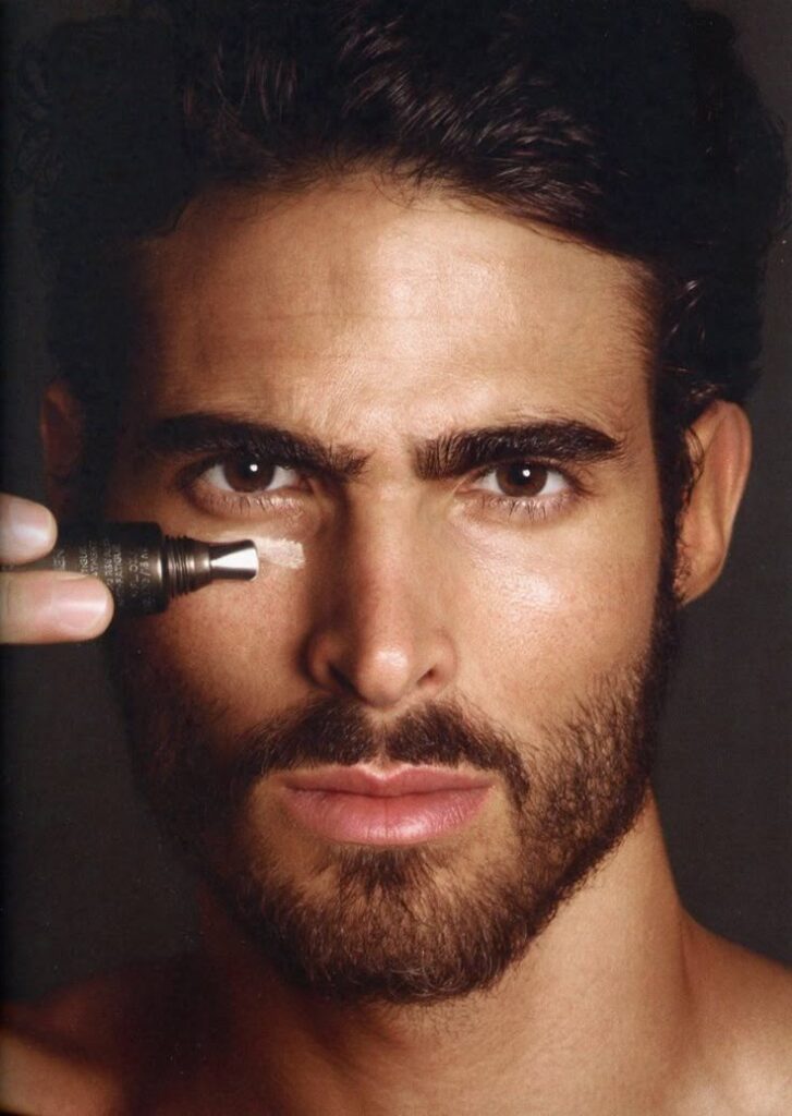 Man applying skincare cream under eye for hydration and rejuvenation.