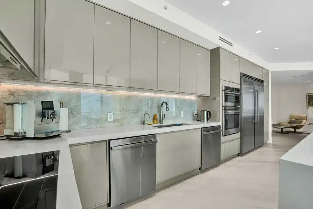 Modern kitchen with sleek cabinetry, stainless steel appliances, and a built-in espresso machine on a quartz countertop.