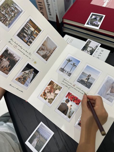 Person creating a scrapbook with beach and wedding photos, adding handwritten captions on a wooden table.